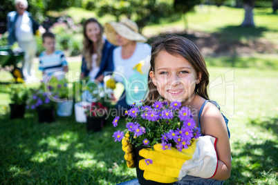Girl holding a flower pot while gardening with family