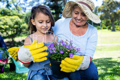 Grandmother and granddaughter holding a flower pot while gardeni