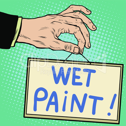 Hand holding a sign wet paint