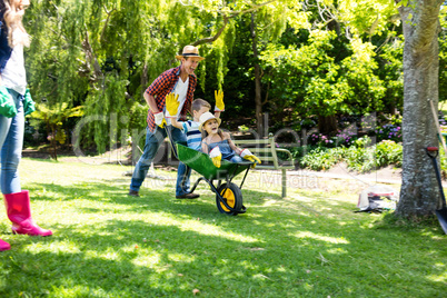 Father carrying his son and daughter in a wheelbarrow