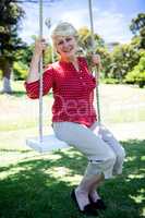 Senior woman sitting on a swing in the park