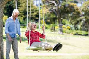 Senior man pushing his partner on swing