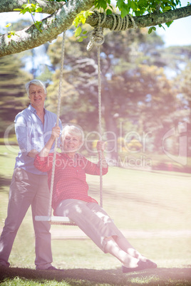 Senior man pushing his partner on swing