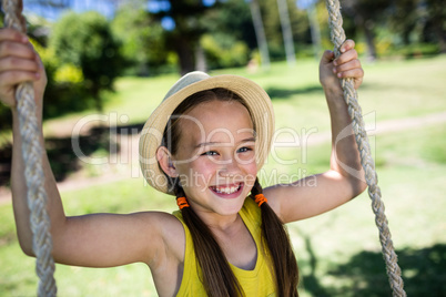 Happy girl sitting on a swing in the park