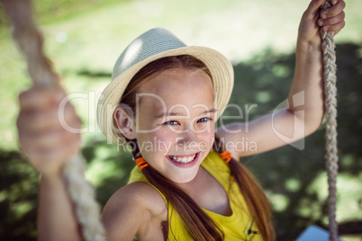 Happy girl sitting on a swing in the park