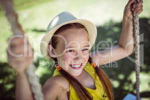 Happy girl sitting on a swing in the park