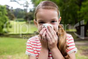 Sick girl sneezing in the park