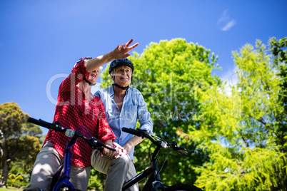 Senior couple talking while cycling in park