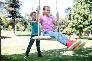 Boy pushing his sister on swing