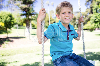 Boy sitting on a swing in the park