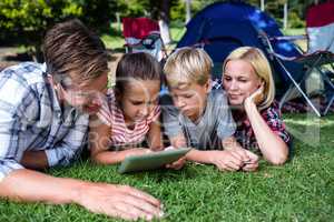 Family lying on grass and using digital tablet