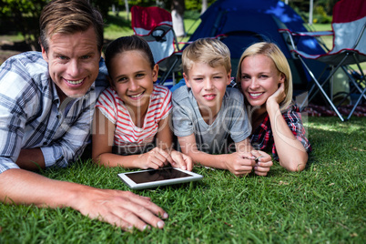 Portrait of a family lying on grass and using digital tablet