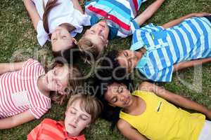 Children lying on grass with eyes closed