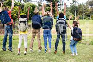Rear view of children with bags jumping together
