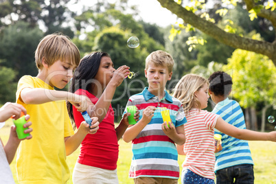 Children blowing bubbles wand in the park