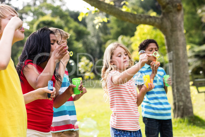 Children blowing bubbles wand in the park