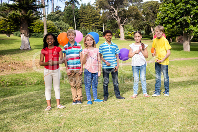 Children standing with balloons in the park