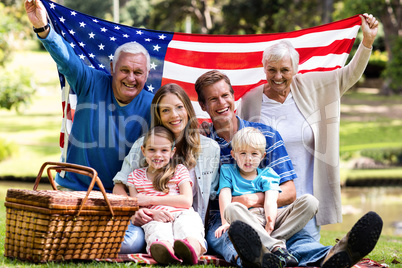 Multi-generation family holding american flag in the park