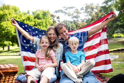 Hapy family holding american flag in the park