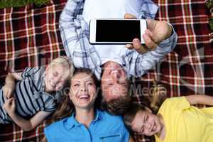 Happy family taking a selfie while lying in the park