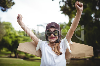 Happy girl standing in park with hands raised