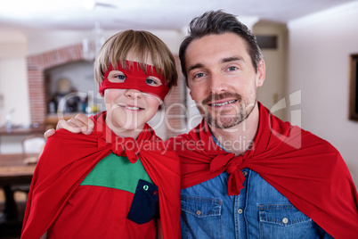 Portrait of father and son pretending to be superhero in living