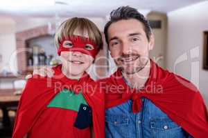 Portrait of father and son pretending to be superhero in living