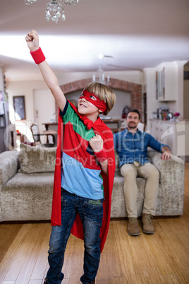 Son pretending to be a superhero while father sitting on sofa Son pretending to be a superhero while father sitting on sofa