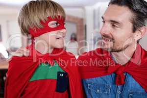 Father and son pretending to be superhero in living room