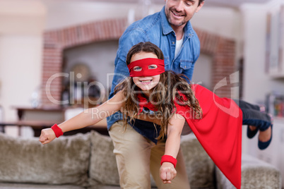 Father and daughter pretending to be superhero in living room