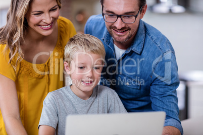 Parents and son using laptop in kitchen