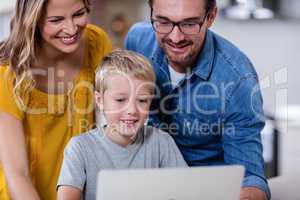 Parents and son using laptop in kitchen