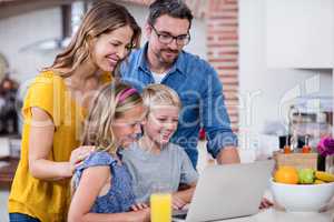 Parents and kids using laptop in kitchen