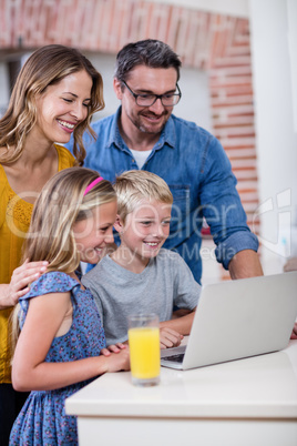 Parents and kids using laptop in kitchen