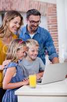 Parents and kids using laptop in kitchen