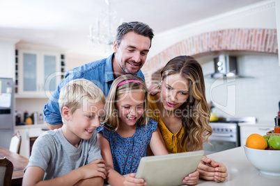 Parents and kids using digital tablet in kitchen