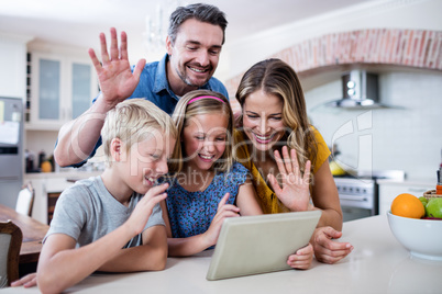 Parents and kids waving hands while using digital tablet for vid