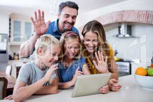 Parents and kids waving hands while using digital tablet for vid