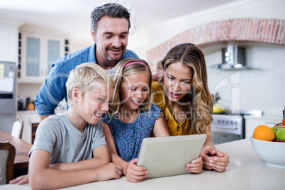 Parents and kids using digital tablet in kitchen