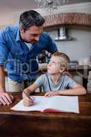 Father helping son with his homework in kitchen