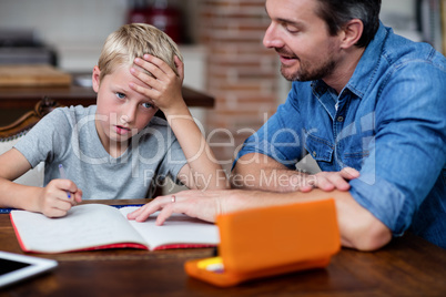 Father helping son with his homework in kitchen