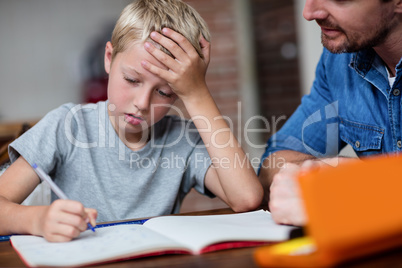 Father helping son with his homework in kitchen