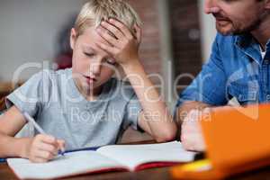 Father helping son with his homework in kitchen