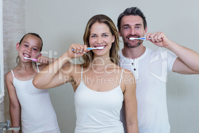 Parents and daughter brushing their teeth in the bathroom