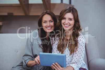 Two beautiful women using a digital tablet in living room