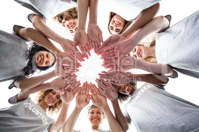 Happy volunteers standing in a circle with their hands together