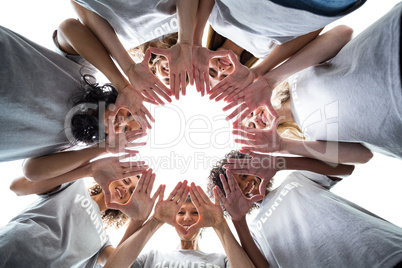 Happy volunteers standing in a circle with their hands together