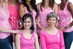 Smiling women in pink outfits posing for breast cancer awareness