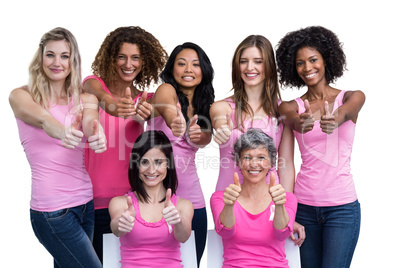 Smiling women in pink outfits showing thumbs up for breast cance