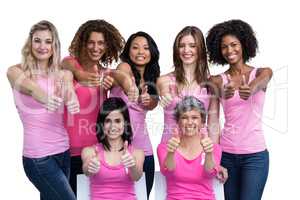 Smiling women in pink outfits showing thumbs up for breast cance